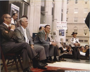 ["Jay Rockefeller (third from left) seated on the Mingo County Courthouse steps campaigning for Governor."]%